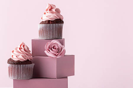 cupcake con decorazioni rosa poggiati su scatole rosa antico